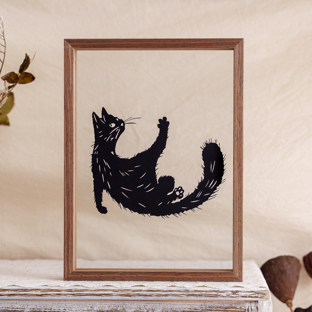 A papercut memorial capturing a playful moment of a cat rolling over, celebrating its mischievous spirit.