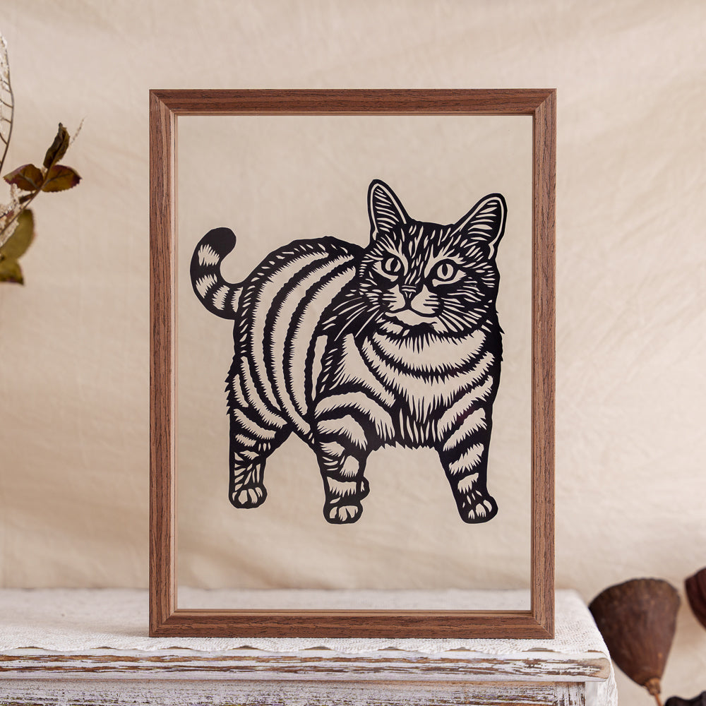 A silhouette paper cut of a chubby cat, finely carved to show expression and fur detail.