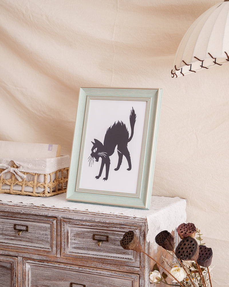 Comedic hand-cut paper artwork depicting a cat's funny pose, placed in a home setting.