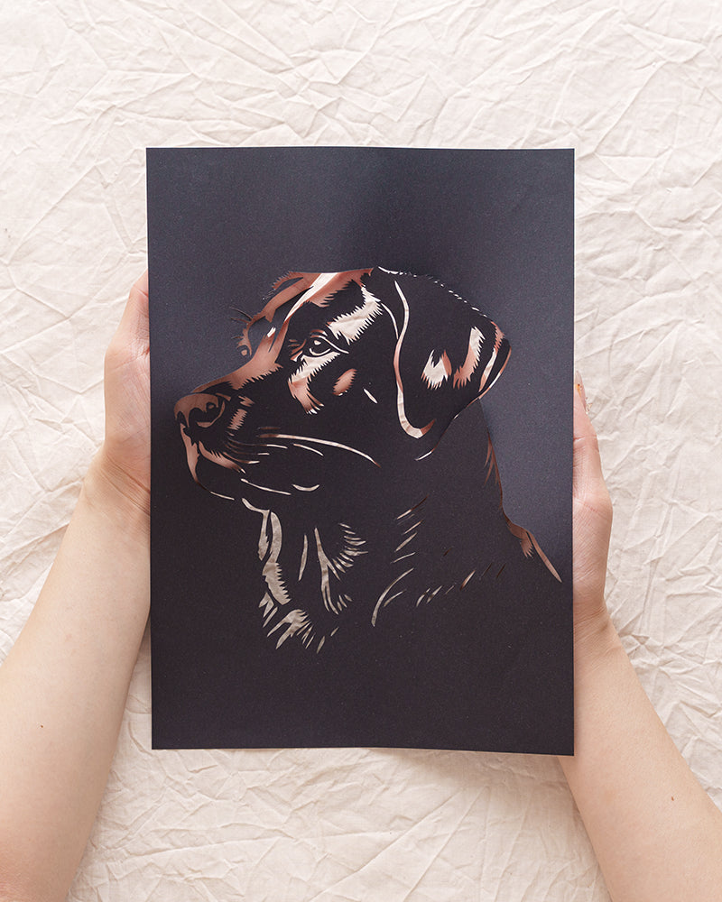 Hand holding custom black dog silhouette paper art