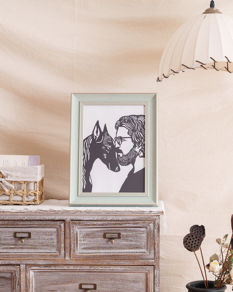  cherished black paper-cut artwork, showing a Doberman Pinscher and its owner with heads touching, displayed on a shelf/table/wall in a home setting. 