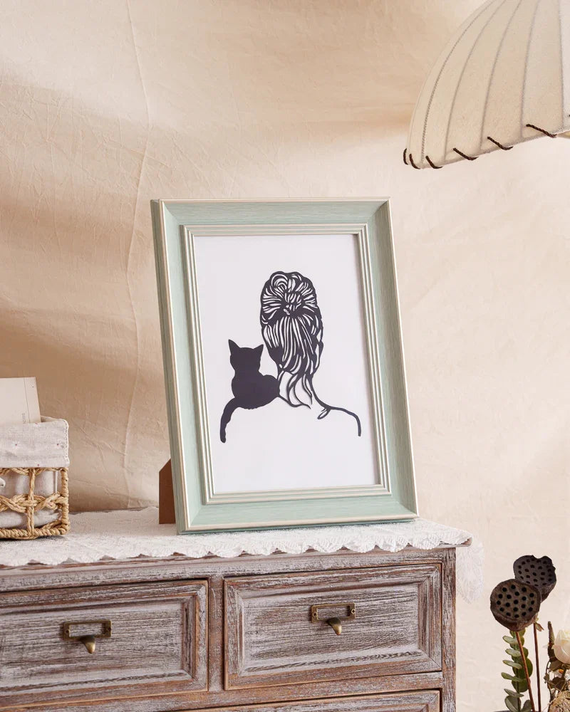 Side-angle shot of a hand-cut paper silhouette capturing a cat curled on its human's shoulder - delicate shadow lines tracing fur contours as their profiles merge into one timeless bond