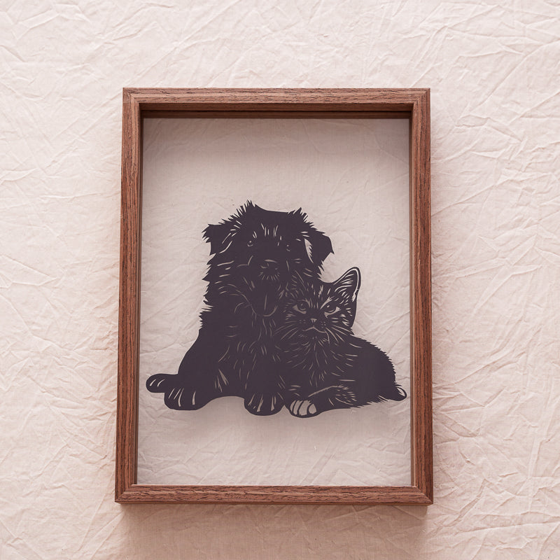 A beautifully designed silhouette papercut featuring both a dog and a cat, celebrating their gentle connection in art form