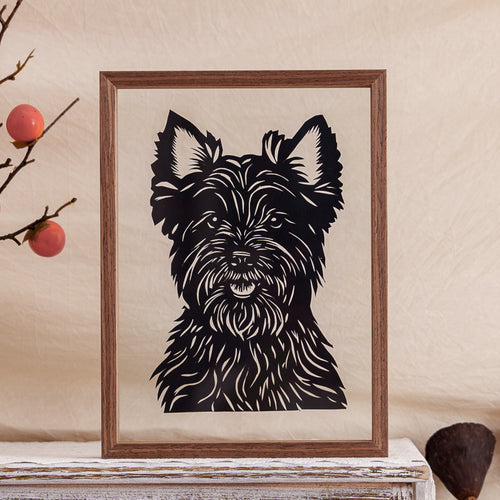 A fluffy dog papercut framed and placed on a wooden table, showcasing the warmth of handcrafted pet memorial art