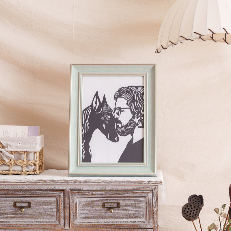  cherished black paper-cut pet memorial, showing a Doberman Pinscher and its owner with heads touching, displayed on a wall in a home setting. 