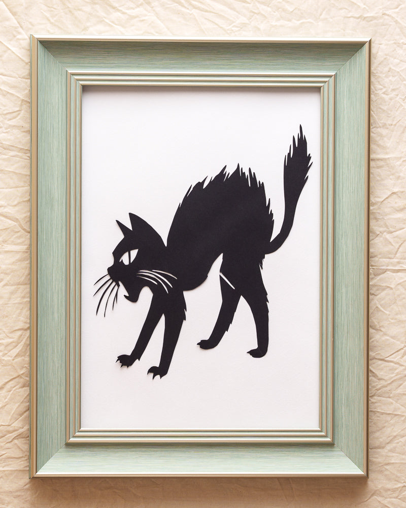 Hand-cut paper artwork of a cat leaping upwards in surprise, single-layer design.