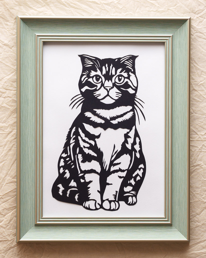This tabby paper-cut dances with life — swatting imaginary dust bunnies just like she never left