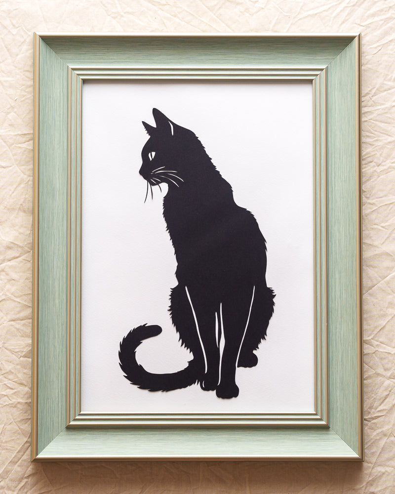 Black paper-cut cat silhouette artwork showing full-body contours on dark background
