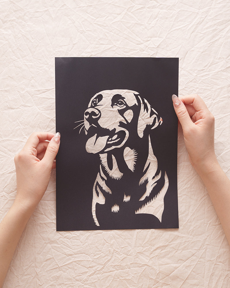 Hand holding a custom Labrador silhouette paper cut