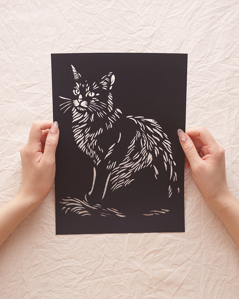 Hand holding a detailed lion cat silhouette paper cut