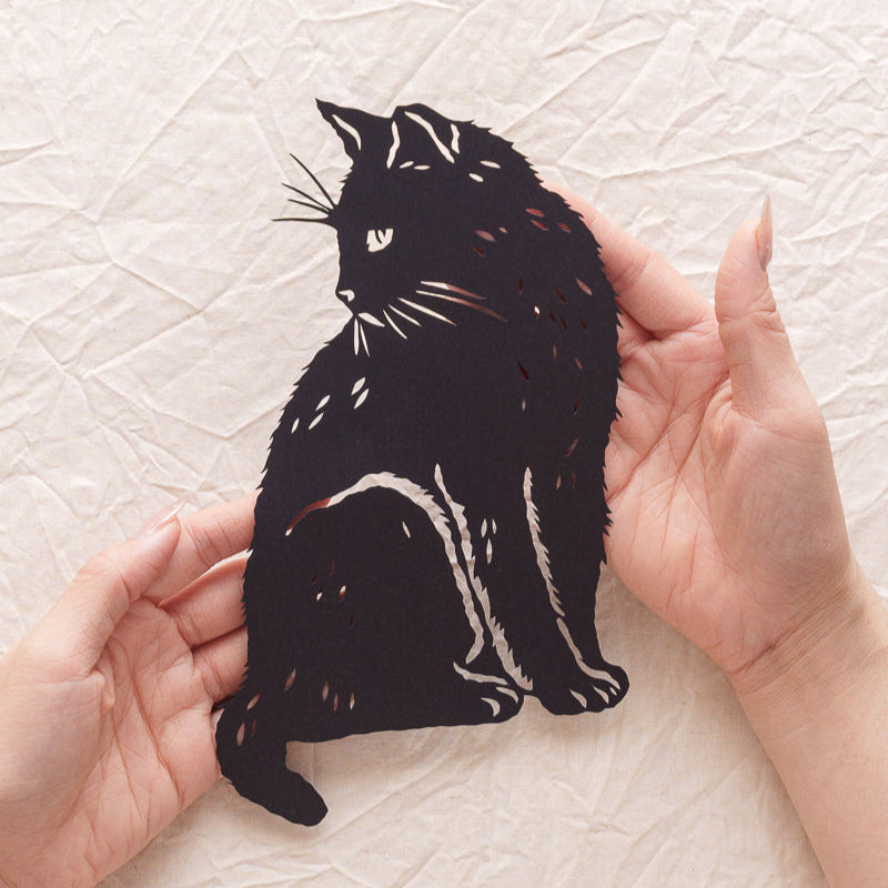 Hand holding a custom cat paper cut memorial, with detailed carving that gives the fur a rich and lifelike texture.