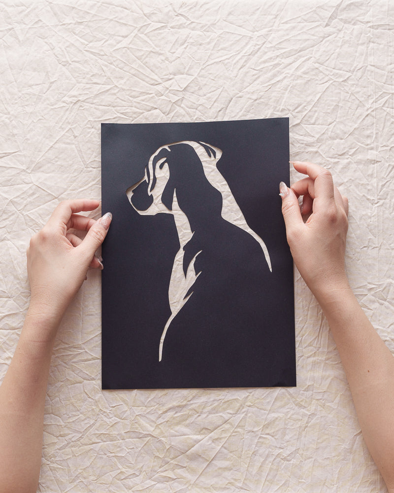 Hand holding a delicate Labrador silhouette paper cut

