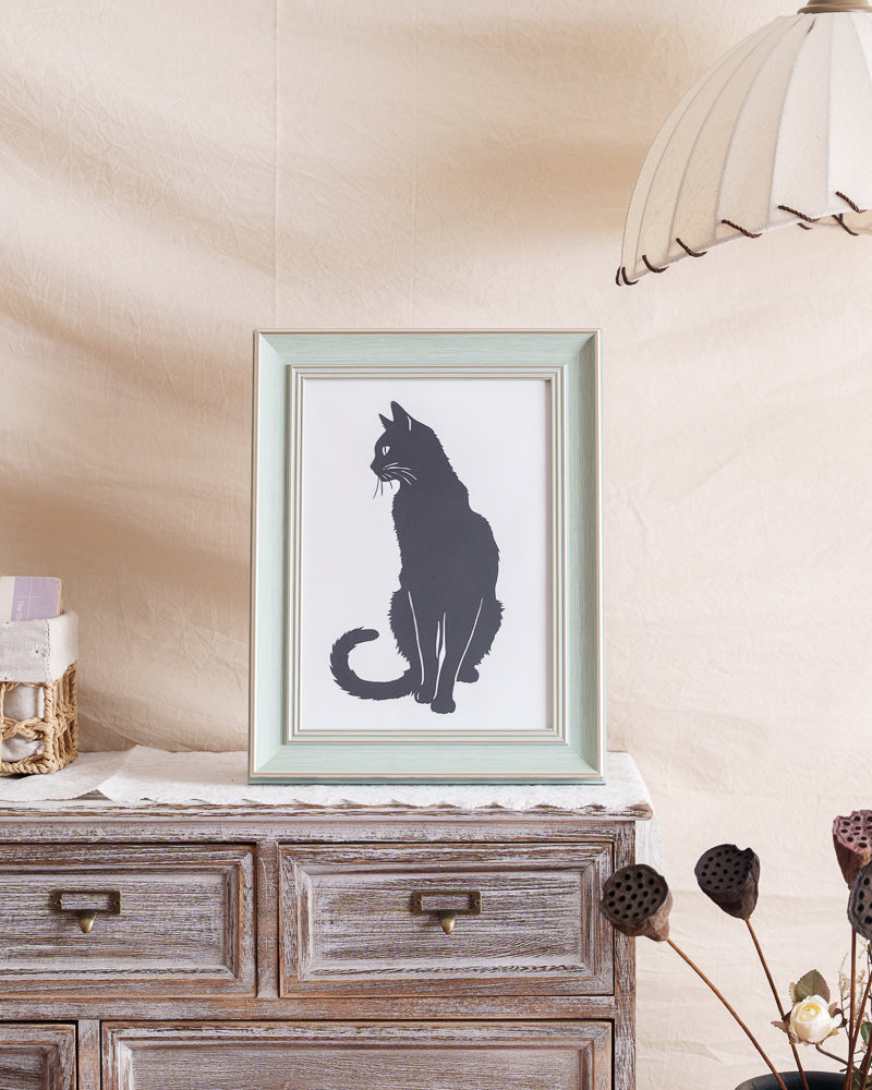 Black cat memorial paper art displayed on home bookshelf near window with natural lighting