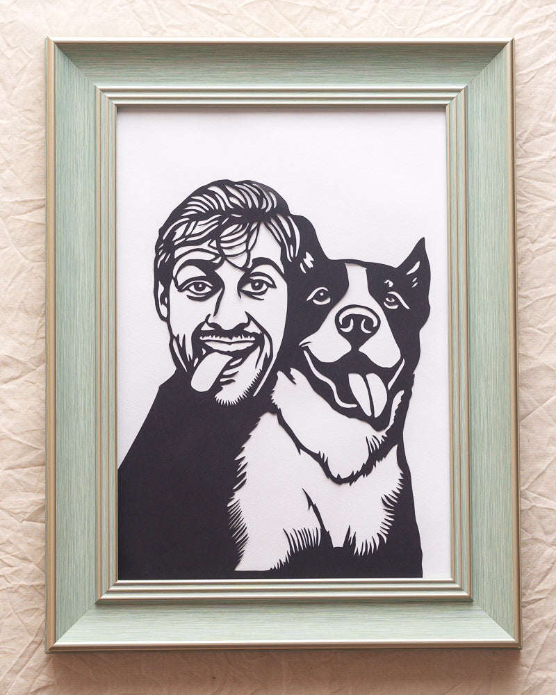 Custom cut-paper portrait of owner embracing their dog, laser-cut from premium black cardstock