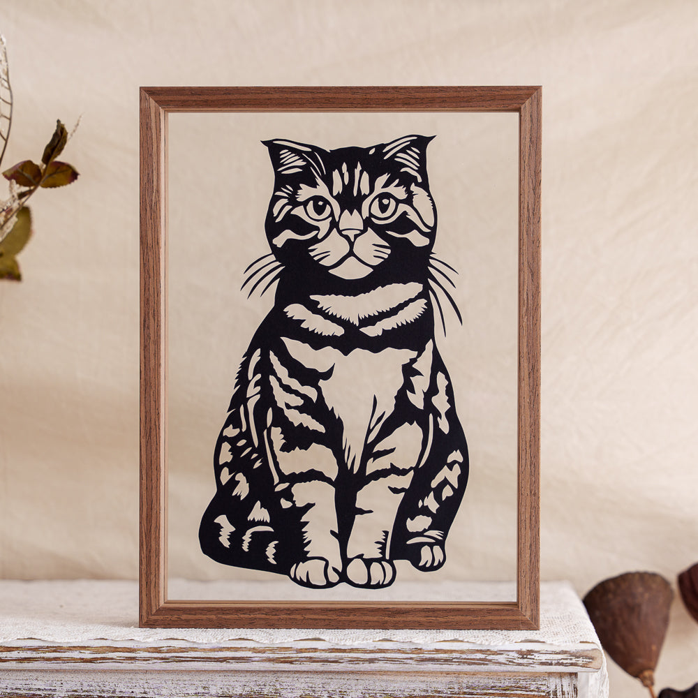 A pet memorial papercut featuring a curious tabby cat in a front-facing silhouette.