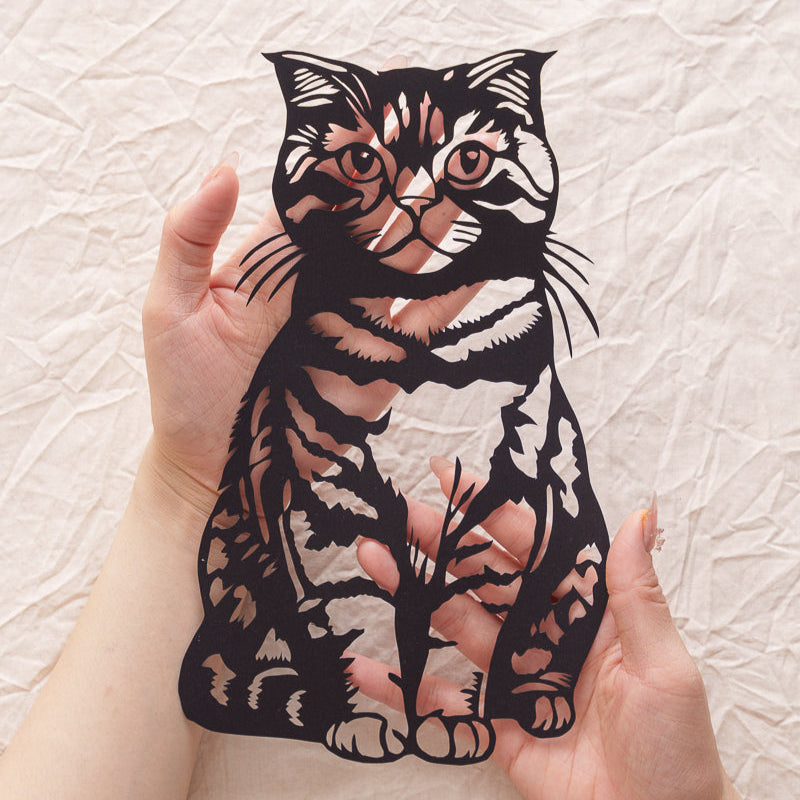 Cradling her paper twin: Silk-textured fur makes phantom purrs rumble under my fingertips 