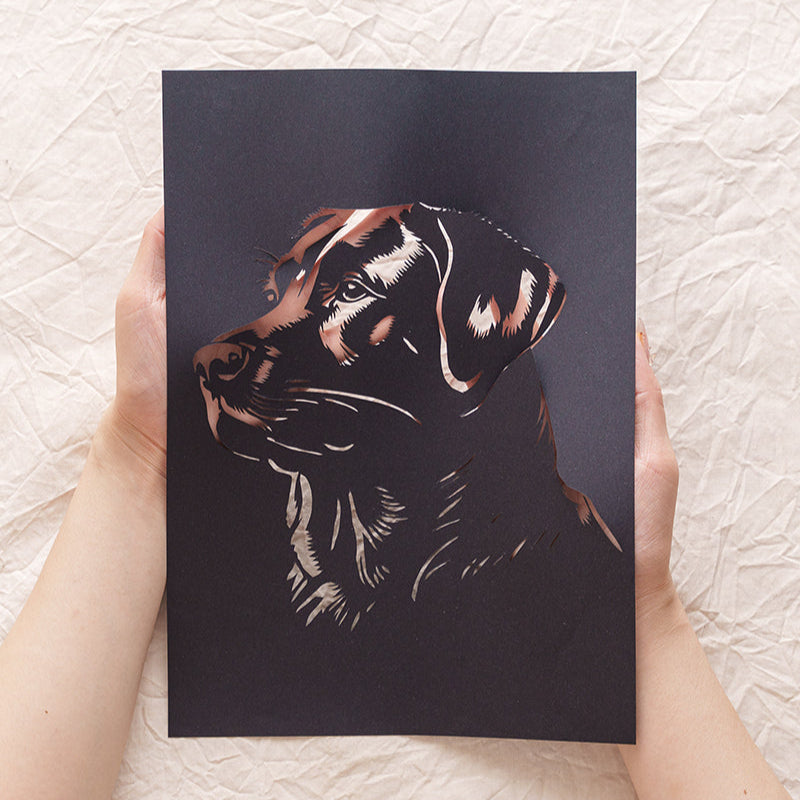 Hand holding custom black dog silhouette paper art