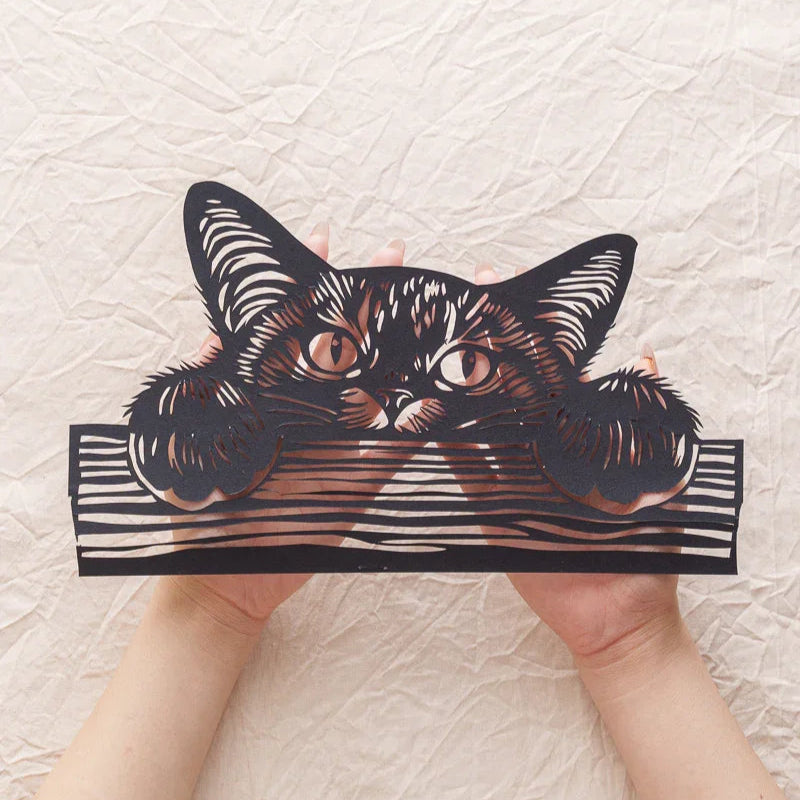 In my hands is a commemorative paper-cut artwork of a kitten peeking