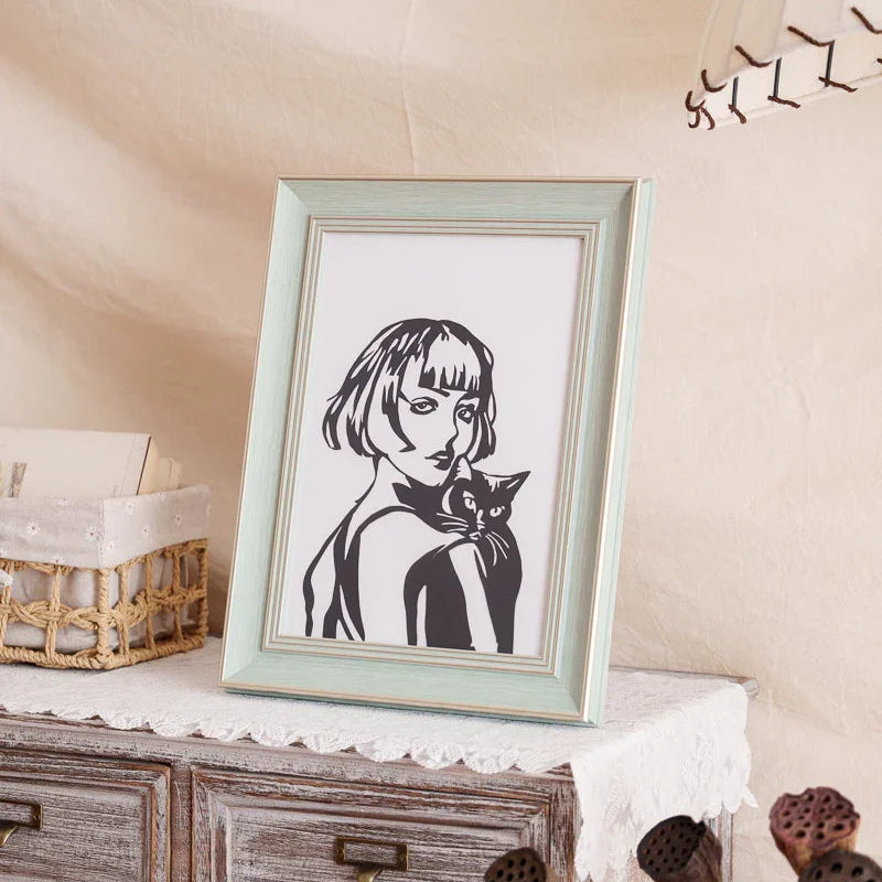 A framed papercut artwork of a woman holding her cat, beautifully displayed at home as a heartfelt tribute and decorative piece.