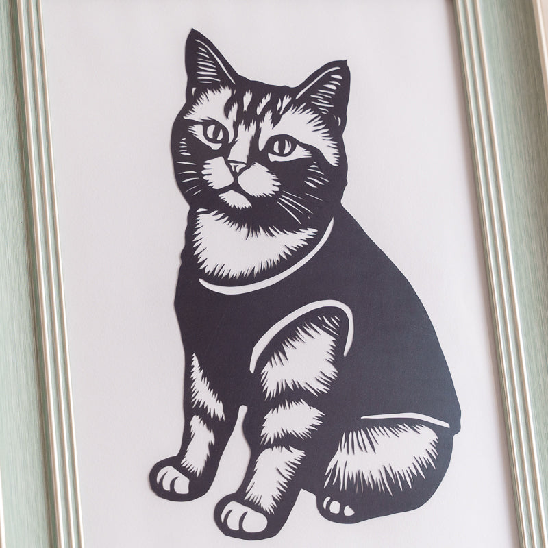 Close-up view of a cat silhouette memorial papercut showing intricate handcrafted details.

