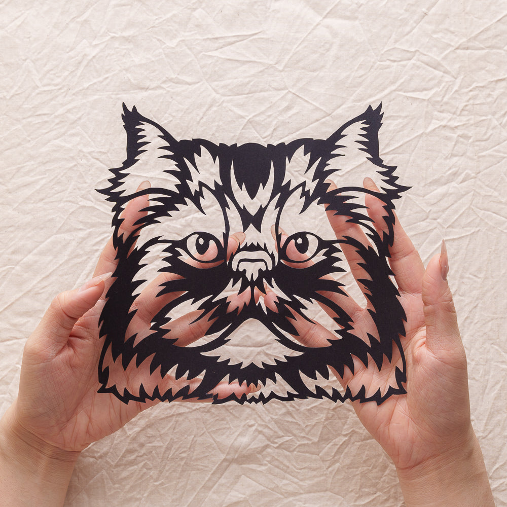 An artist holding a handcrafted cat memorial silhouette paper cut