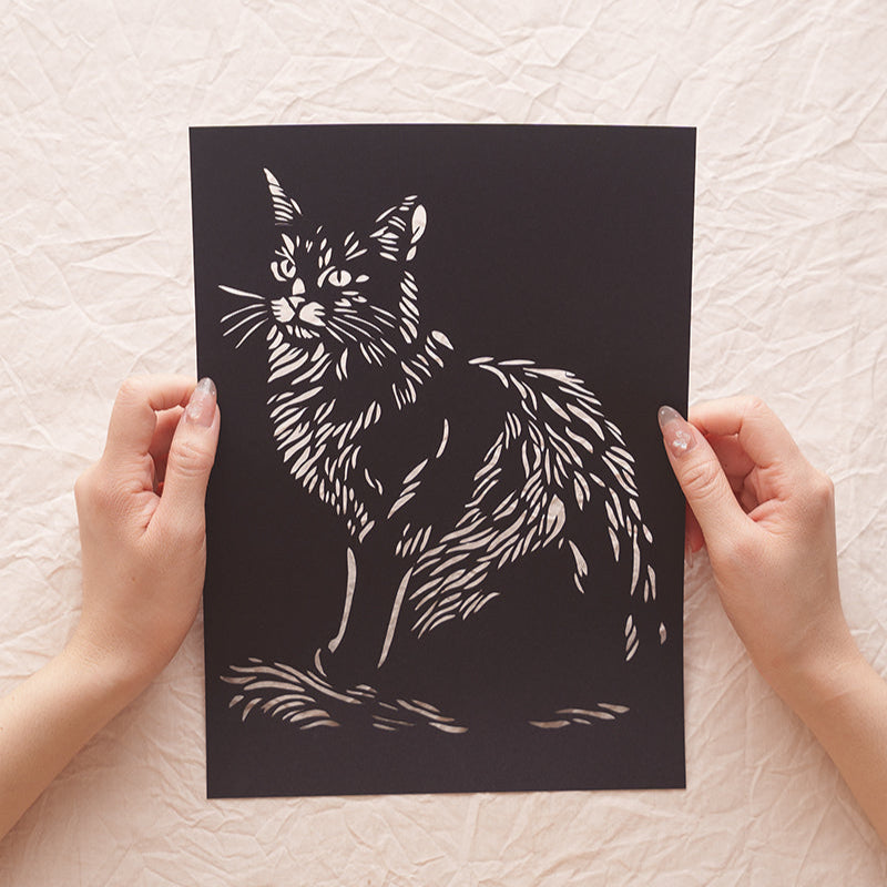 Hand holding a pet memorial — a handcrafted cat portrait paper cut