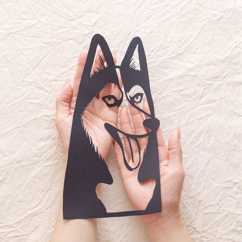 An artist holding a freshly carved Husky dog memorial paper cut
