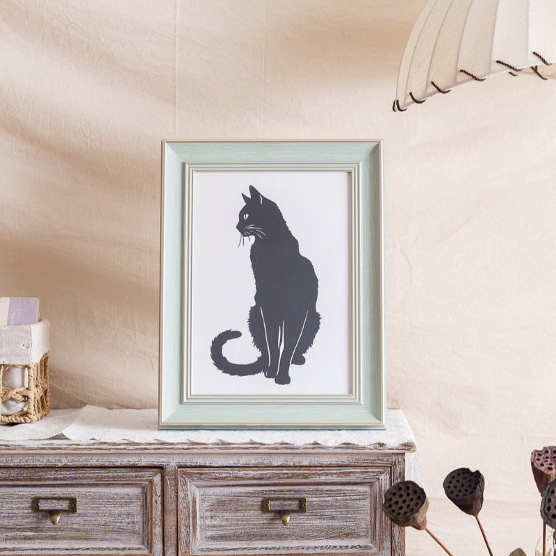 Black cat memorial paper art displayed on home bookshelf near window with natural lighting