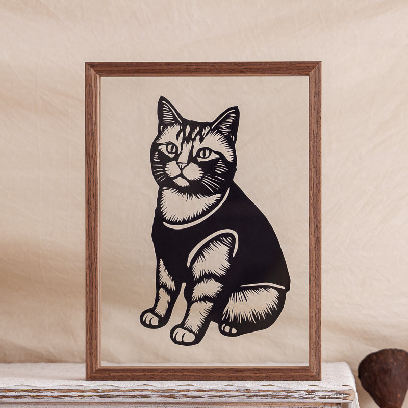 A sitting cat silhouette memorial papercut framed in a clear glass display.